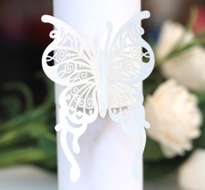 Détail d'un rond de serviette papillon ajouré au laser en papier blanc nacré élégant
