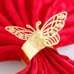 Exquisite gold butterfly napkin ring with laser-cut hollow design on red fabric background