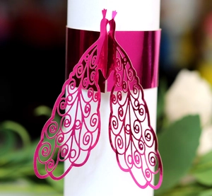 Laser-cut peacock paper napkin rings in metallic magenta with intricate hollow patterns