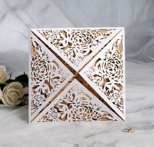 Close-up of laser-cut white floral wedding invitation with elegant gold insert card