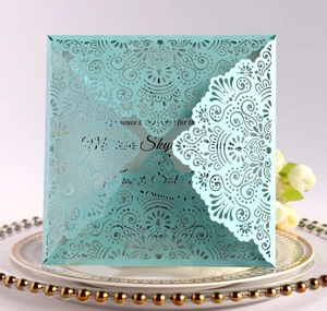 Detail of laser-cut tiffany blue invitation card with floral lace on a porcelain plate