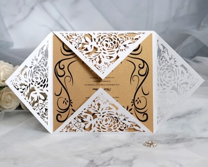 Detail of laser-cut white floral wedding invitation with elegant gold insert card
