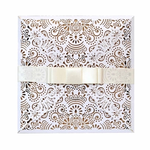 Laser-cut white wedding invitation with symmetrical mandala pattern and cream ribbon bow