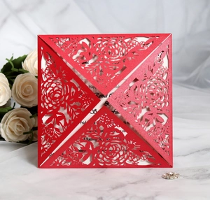 Detail of red laser-cut floral wedding invitation on marble background with roses