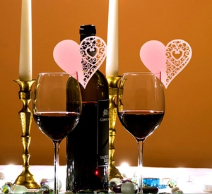 Detail of pink heart-shaped laser-cut place cards on wine glasses in festive banquet setting