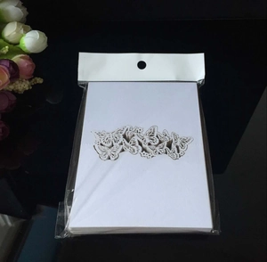 Detail of white butterfly laser-cut place cards in plastic packaging on black background