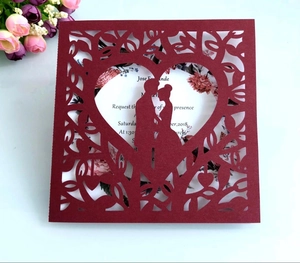 Macro shot of laser-cut burgundy heart wedding invitation with floral printed insert