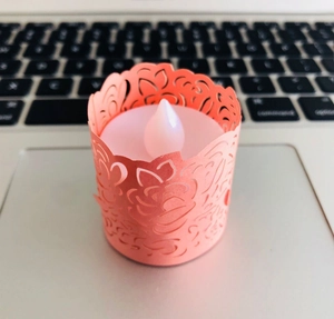 Detail view of pink laser-cut flower patterns on an LED decorative tea light candle lamp