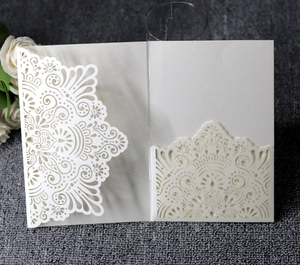 Detail of laser-cut ivory mandala wedding invitation shell on dark fabric background