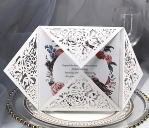 Elegant white laser cut wedding invitation with floral insert and birds on dining plates