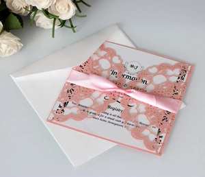Detail van de lasergesneden trouwuitnodiging met roze omslag en een satijnen strik