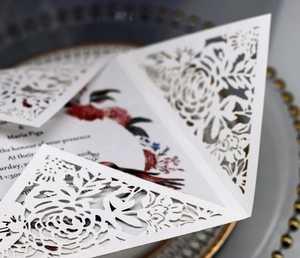 Macro shot of white laser-cut floral wedding invitation on pearlized paper texture