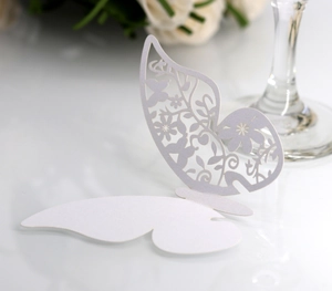 Macro detail of laser-cut white butterfly place card with elegant floral hollow patterns