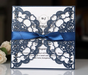 Detail van lasergesneden marineblauwe uitnodiging met koningsblauw lint en bloemen