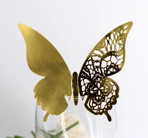 Macro detail of a laser-cut gold butterfly place card on a transparent glass rim