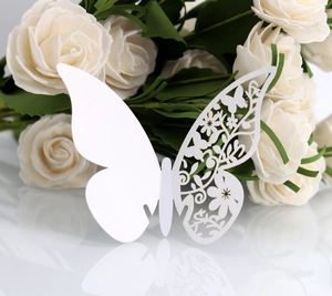 Macro view of a laser-cut white butterfly card with delicate floral hollow patterns