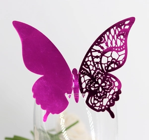 Detailed macro view of a magenta hollow laser-cut butterfly card on a glass rim