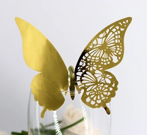 Detailed view of golden 3D butterfly decoration with laser cut pattern on glass rim