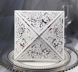 Detailed macro view of laser-cut floral pattern on elegant white wedding invitation