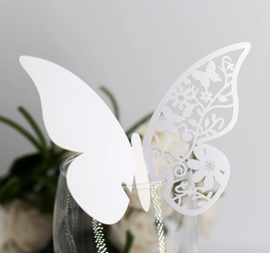 Detail of laser-cut white butterfly glass card with floral patterns for weddings