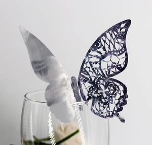 Detailed macro view of laser-cut silver 3D metal butterfly on elegant wine glass rim