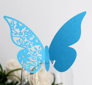 Blue laser-cut paper butterfly place card on wine glass rim for weddings and party decor