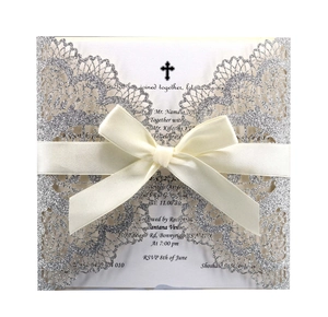 Detail of silver glitter laser-cut wedding invitation with cream ribbon bow and inner page