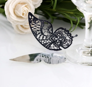 Detailed close-up of laser-cut black paper butterfly place card for wedding glassware