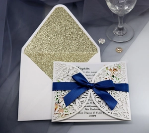 Elegant laser-cut rose wedding invitation set with navy bow and gold glitter envelope