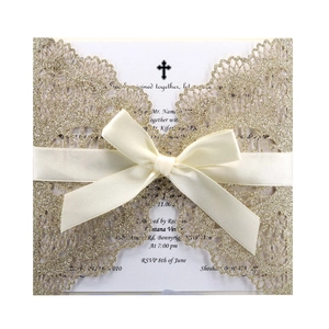 Macro detail of laser-cut glitter wedding invitation with champagne gold cross and silk bow