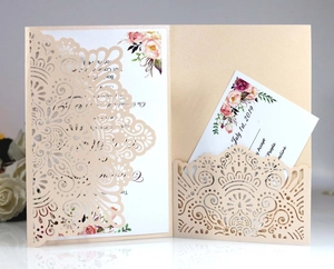 Detail of laser-cut champagne gold wedding invitation with floral patterns and cards