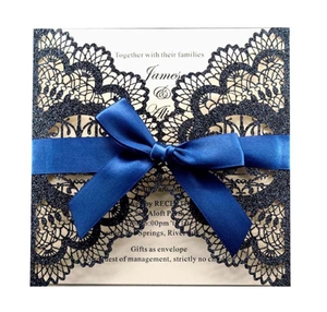 Detail of laser-cut navy glitter wedding invitation with satin ribbon and elegant bow