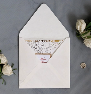 Detail of laser-cut floral wedding invitation with cream envelope and gold-edged card