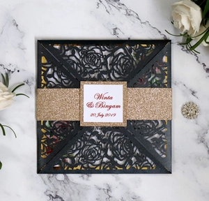 Detail of laser-cut black floral wedding invitation with gold glitter band and custom name tag