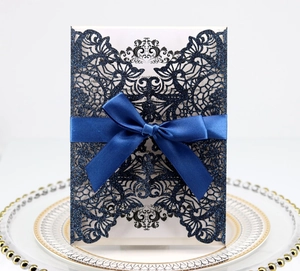 Close-up of laser cut dark blue glitter invitation with elegant ribbon bow detail