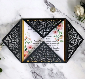 Close-up of laser-cut rose hollow invitation with pink floral inner card on marble