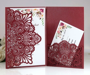 Macro shot of burgundy laser-cut wedding invitation with elegant floral insert and RSVP card