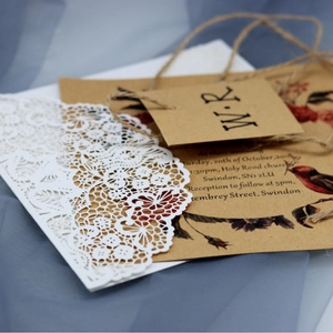 Elegant laser-cut white lace wedding invitation with vintage floral kraft card and twine