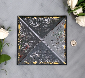 Detailed laser-cut charcoal grey wedding invitation with elegant rose patterns and gold lining