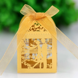 Golden laser-cut wedding favor box with romantic couple silhouette and silk ribbon bow