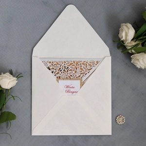 Détail d'un faire-part de mariage découpé au laser avec enveloppe blanche et bord doré