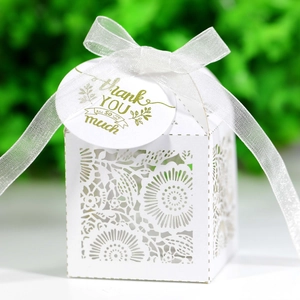 White laser-cut hollow candy gift box with floral pattern and white ribbon bow decoration