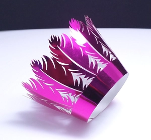Detail of pink laser-cut cupcake wrappers with intricate feather and crown patterns