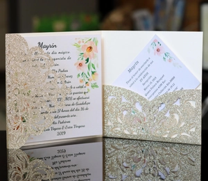 Detail of laser-cut gold glitter invitation cover with elegant floral printed inner card