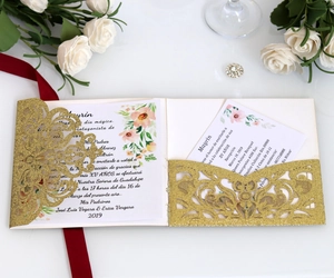 Detail of laser-cut gold glitter wedding invitation with elegant rose pattern cards