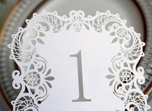 Macro shot of white pearlescent table card with laser-cut lace and gray number 1