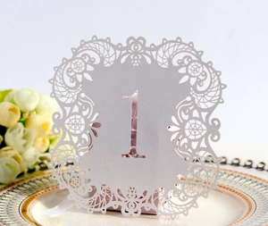 Detail of laser-cut wedding table number card with lace edges on a decorative plate