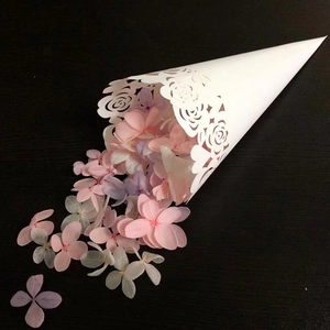 Weiße lasergeschnittene Papiertüte für Hochzeitsblüten auf schwarzem Hintergrund