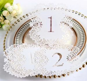 Close-up of laser-cut white wedding table numbers 1 and 2 with elegant lace hollow design