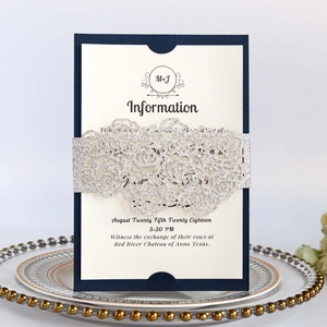 Close-up of navy blue laser-cut invitation with silver glitter floral band and inner card